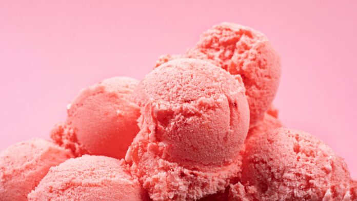 A mound of pink ice cream set against a pink background, featuring a Taylor 024761 lifter arm.